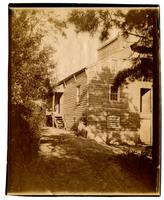 [Man with kittens near wooden house] [graphic].