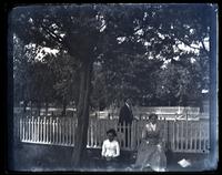 [Man, woman, and girl posed by row of fences in field] [graphic].