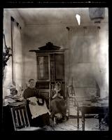 [Interior of unidentified residence, possibly Avocado, with two women on rockers doing handiwork in front of a secretary]