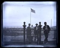 [View from Sea Girt. Front fence of Avocado. Marriott C. Morris, Shober Kimber, and a woman, possibly Anne Emlen, by iron fence on beach. American flag flying in background] [graphic].