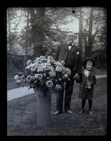 Elliston P. Morris with child [Elliston P. Morris Jr.], standing outside near a large vase of roses [graphic].