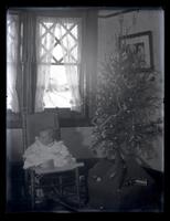[Baby on chair near Christmas tree in front of window] [graphic].