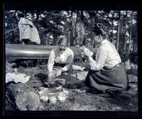 [Two women preparing food], canoeing, Egg Harbor River, NJ [graphic].