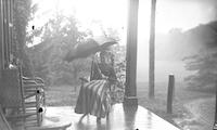 [Bertha Taylor Webster sitting with an umbrella on the porch of Mt. Equity, Pennsdale, Pa.] [graphic].