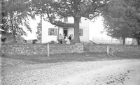 [Group sitting on the side porch of an unidentified residence] [graphic].