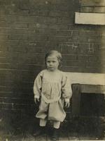 Young child standing in front of brick wall, Philadelphia.