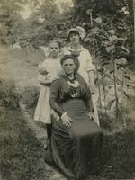 Group portrait of woman sitting in yard with two girls, Philadelphia.