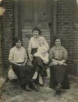 Three women and infant sitting on doorstep, Philadelphia.