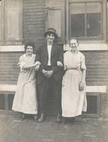 Young man and two girls standing in front of brick wall and windows, Philadelphia.
