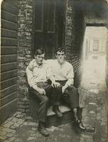 Two young men sitting on stoop in front of door in alley, Philadelphia.