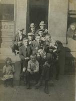 Group of men and children posing on steps of brownstone house, Philadelphia.