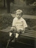 Little boy with leg braces sitting on bench, Philadelphia.
