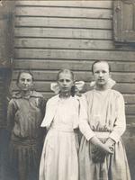 Three girls standing in front of wooden house, Philadelphia.