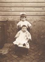 Two young children on sidewalk with rocking chair, Philadelphia.