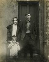 Man, woman, and little boy standing in front of door, Philadelphia.