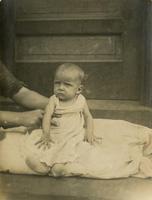 Infant sitting on pillow on doorstep, Philadelphia.