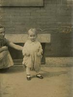 Child standing on sidewalk with woman, Philadelphia.