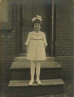 Little girl with a bow in her hair standing in front of a door, Philadelphia.
