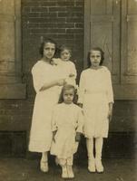 Woman and three children standing in front of brick wall and shutters, Philadelphia.