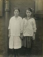 Two girls standing in front of a house or factory, Philadelphia.