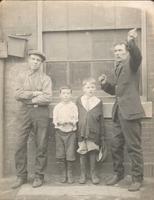 Two men and two boys in front of factory window, Philadelphia.