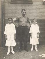 Man standing with two girls in front of brick wall, Philadelphia.
