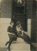 Two women sitting on marble steps in front of door, Philadelphia.