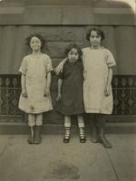 Three girls standing in front of a brownstone building, Philadelphia.