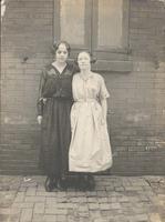 Two young women in front of brick wall and shutters, Philadelphia.