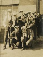 Eight men and boys standing outside a brick building, Philadelphia.