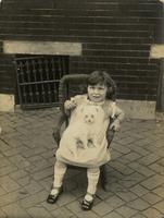 Little girl and dog in wicker chair on sidewalk, Philadelphia.