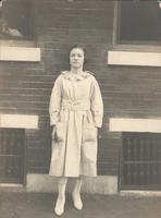 Young woman standing in front of brick wall and windows, Philadelphia.