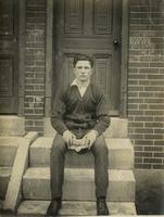 Young man in cardigan sweater sitting on marble steps, Philadelphia.