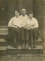 Man and two women sitting on a wooden stoop, Philadelphia.