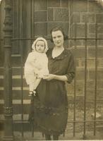 Young mother holding infant standing in front of church, Philadelphia.