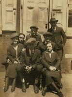 Five men and two women on the front steps of a brick house, Philadelphia.