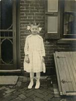 Young girl standing outside a house, Philadelphia.