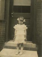 Little girl in dress standing on marble step, Philadelphia.