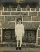 Little boy with frilly shirt standing in front of a stone porch, Philadelphia.