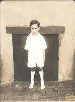 Boy wearing white outfit standing in front of wall, Philadelphia.