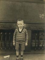 Little boy wearing printed sweater standing in front of brownstone house, Philadelphia.