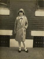 Girl wearing hat standing in front of brick house, Philadelphia.