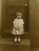 Little girl standing on brownstone steps in front of door, Philadelphia.
