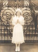 Girl in white dress standing in front of wrought iron gate, Philadelphia.