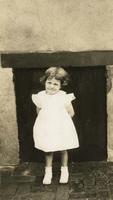 Little girl in summer dress standing in front of wall, Philadelphia.