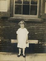 Little girl in summer dress standing in front of brick house, Philadelphia.