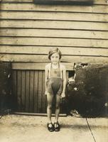 Little girl in sunsuit standing in front of wooden house, Philadelphia.