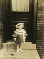 Little girl in knitted winter coat and hat standing on steps, Philadelphia.