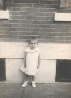 Little girl in dress in front of house, Philadelphia.