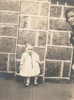 Small girl standing in front of stone wall, Philadelphia.